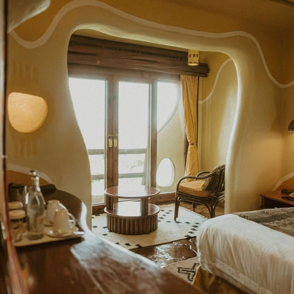 Cave-style Standard King Room with curved plaster walls and glass doors leading to a balcony at Mara Serena Safari Lodge