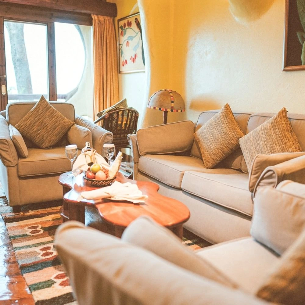 Cozy beige sofas around a wooden table in The Suite at Mara Serena Safari Lodge, reflecting the charm of unique resorts