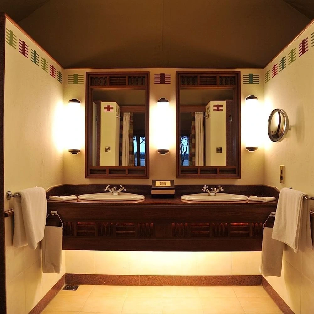 Double vanity and wooden mirrors in the Morani Deluxe Tent at Sweetwaters Serena Camp, reflecting the charm of unique resorts
